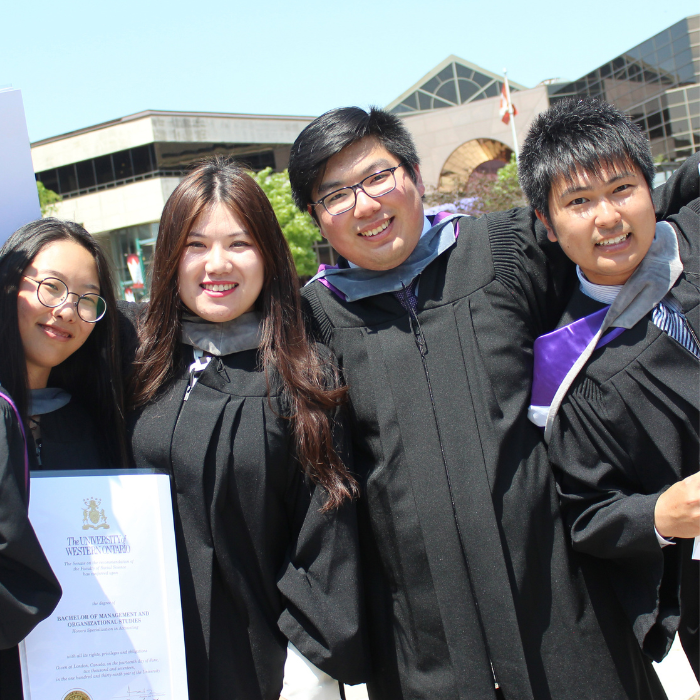 A group of gradudates posing for a photo with their degrees