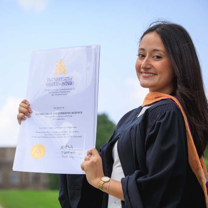A graduate posing and smiling with their degree
