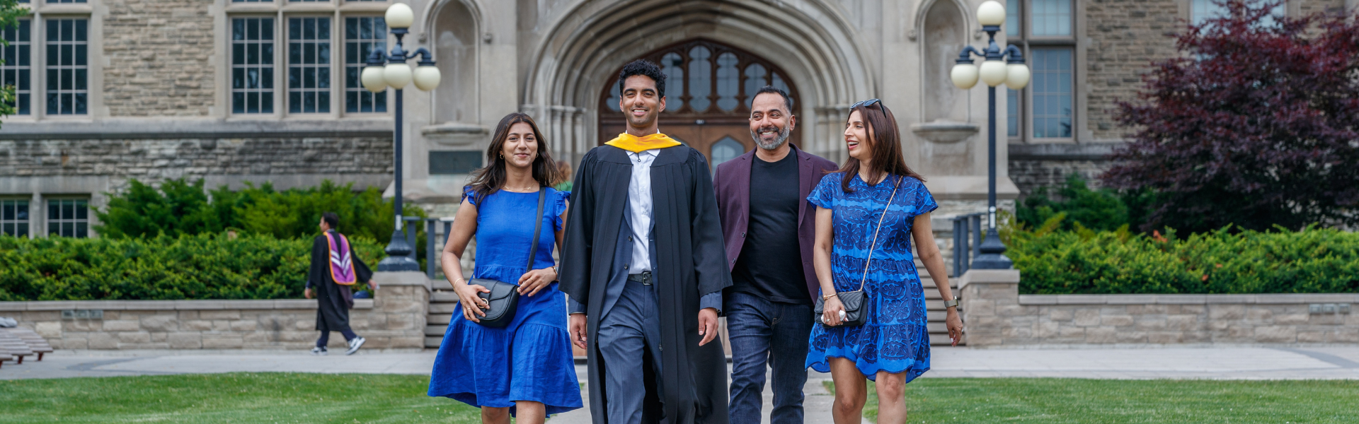 A graduate and their family walking together on campus
