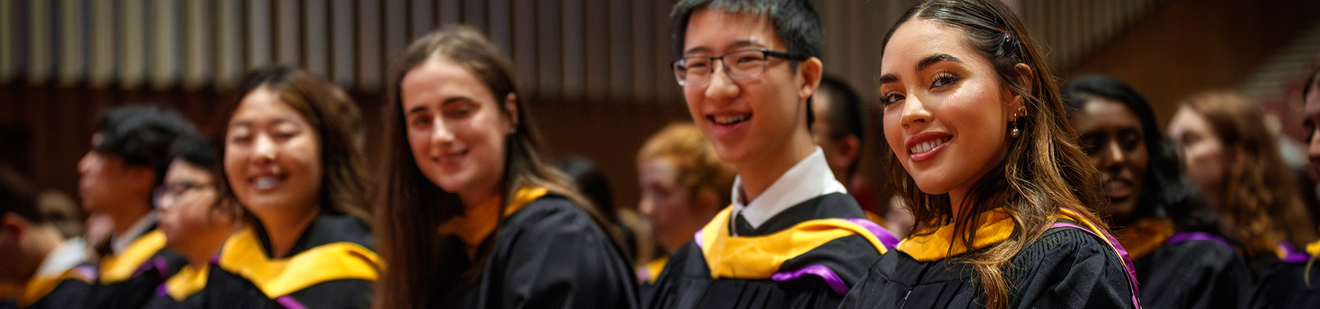 graduates at a convocation ceremony smiling at camera