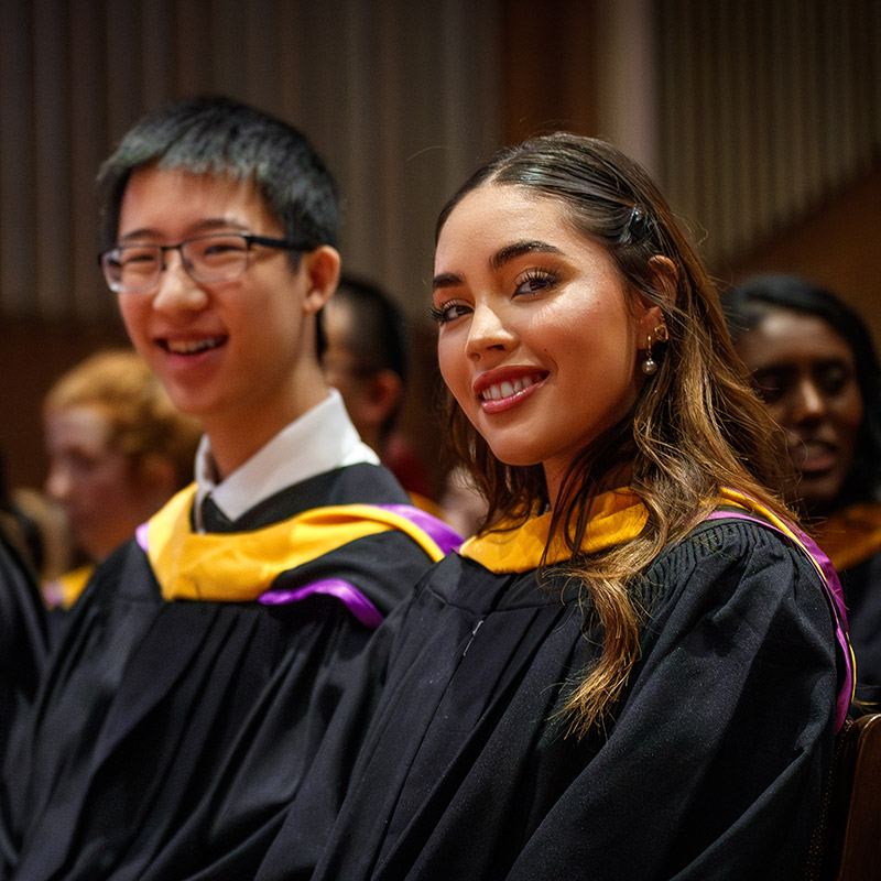 graduates at a convocation ceremony smiling at camera
