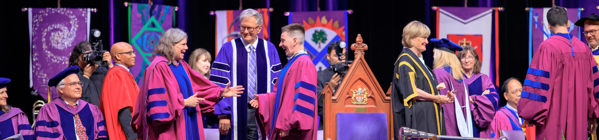 Staff sitting on the stage at convocation smiling and applauding