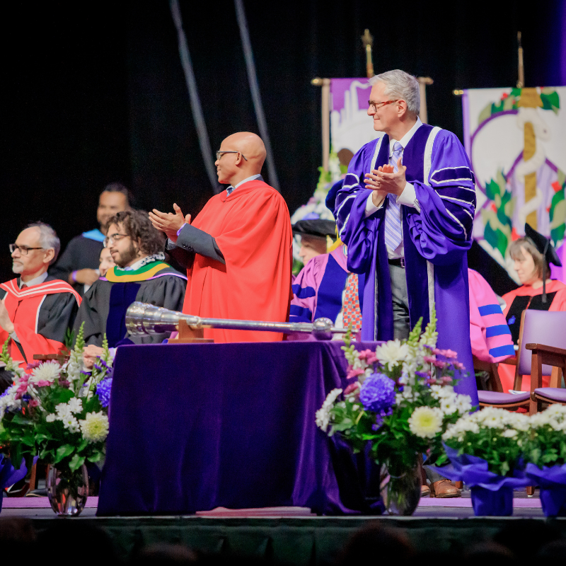 Two people standing on the Convocation stage appluading