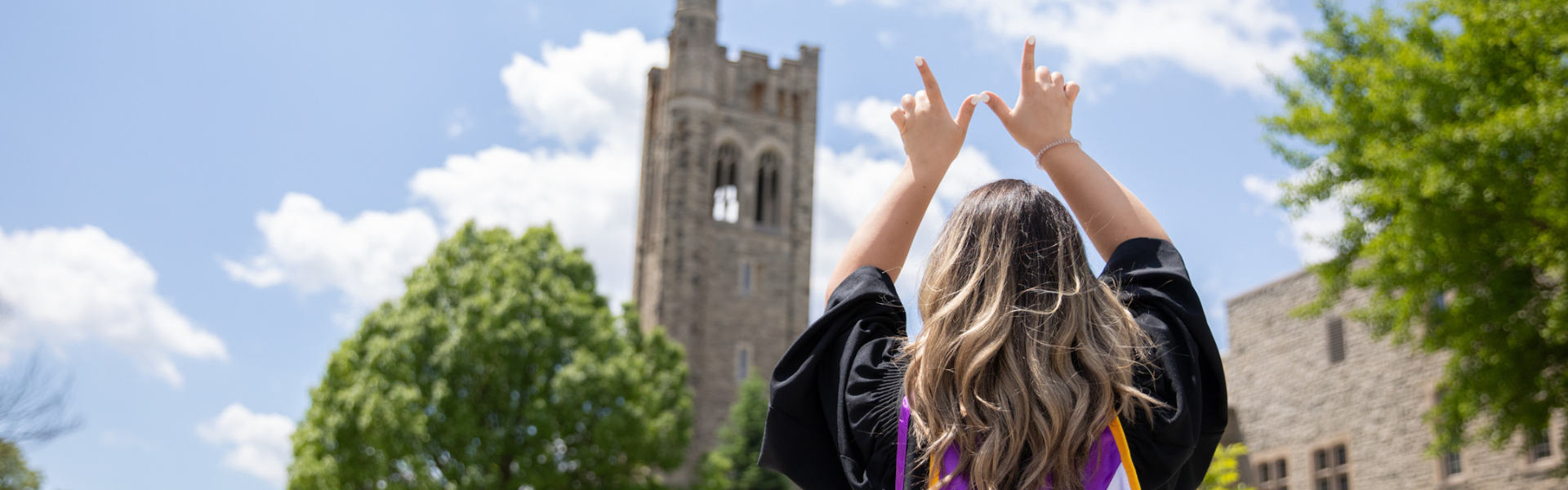 A graduate standing in front of UC hill