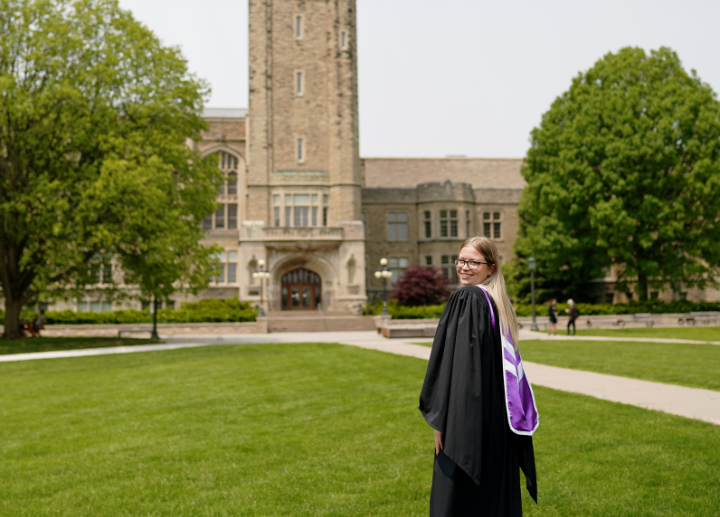 A graduate in academic regalia posing in front of University College