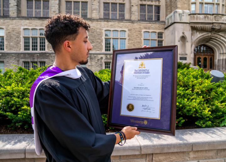 A graduate holding their framed diploma