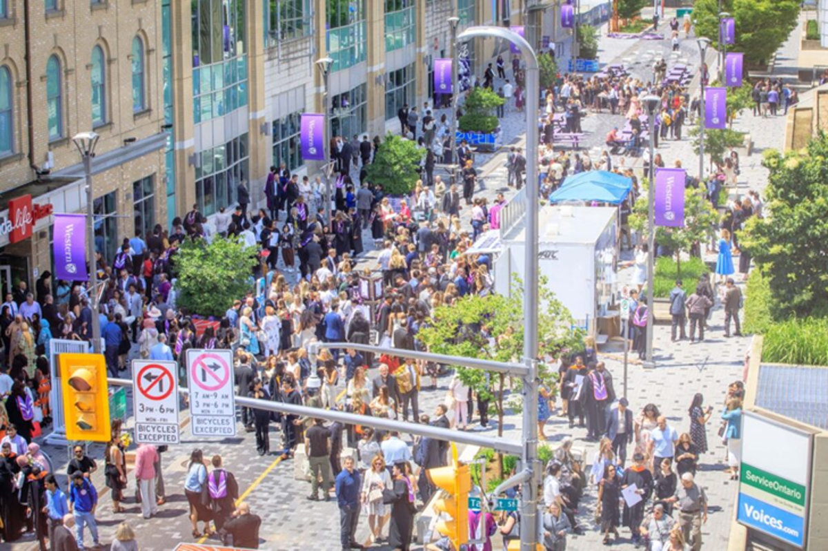 Graduates and guests mingle on Dundas Place outside after a ceremony in Spring 2025.