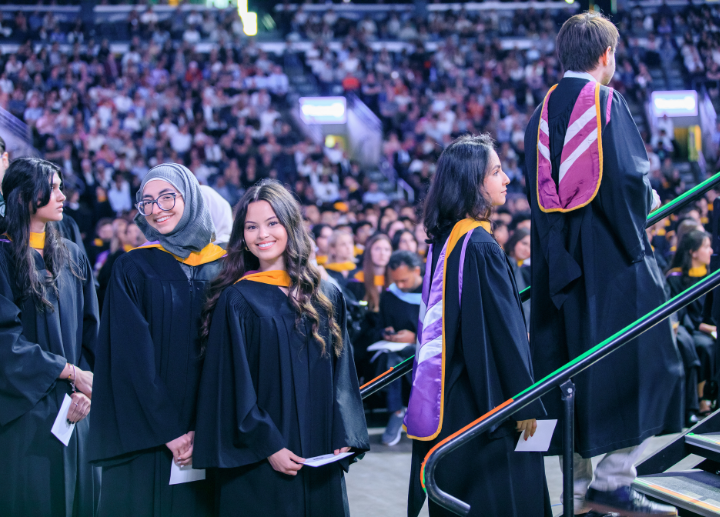 A graduate looking up from their seat in Canada Life Place and smiling