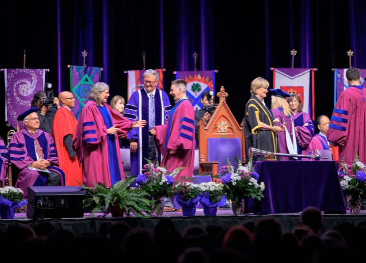 A smiling graduate seated at Convocation