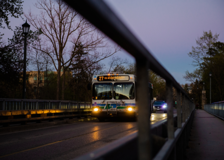 A close up of a London City Bus driving through campus in the evening